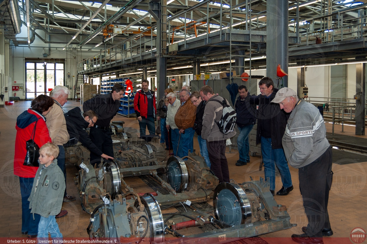 Foto der Teilnehmergruppe im Betriebshof Rosengarten in der Werkstatthalle beim Betrachten eines Einzelrad-Einzelfahrwerks des Niederflurwagens MGT6D